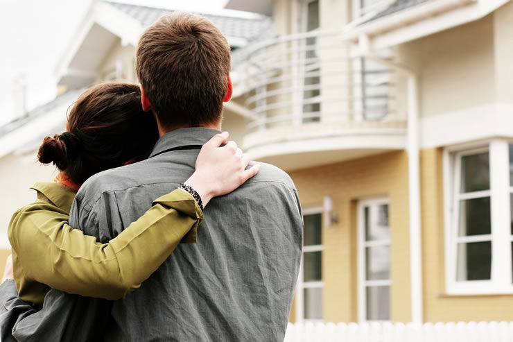 A couple standing together in front of a townhouse